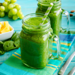 Two mason jars of green smoothie recipes with grapes, pineapple, spinach, and almonds.