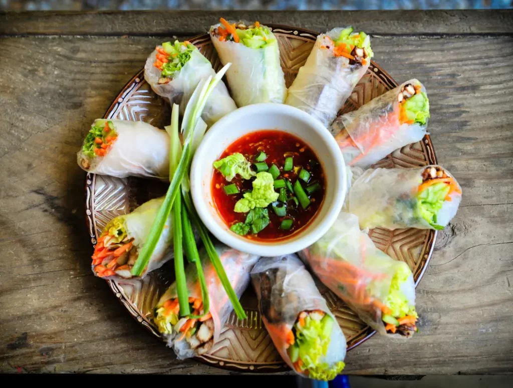 Fresh Vegan Spring Rolls served with homemade peanut sauce on a white plate.