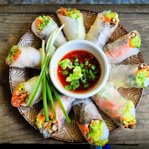 Fresh Vegan Spring Rolls served with homemade peanut sauce on a white plate.