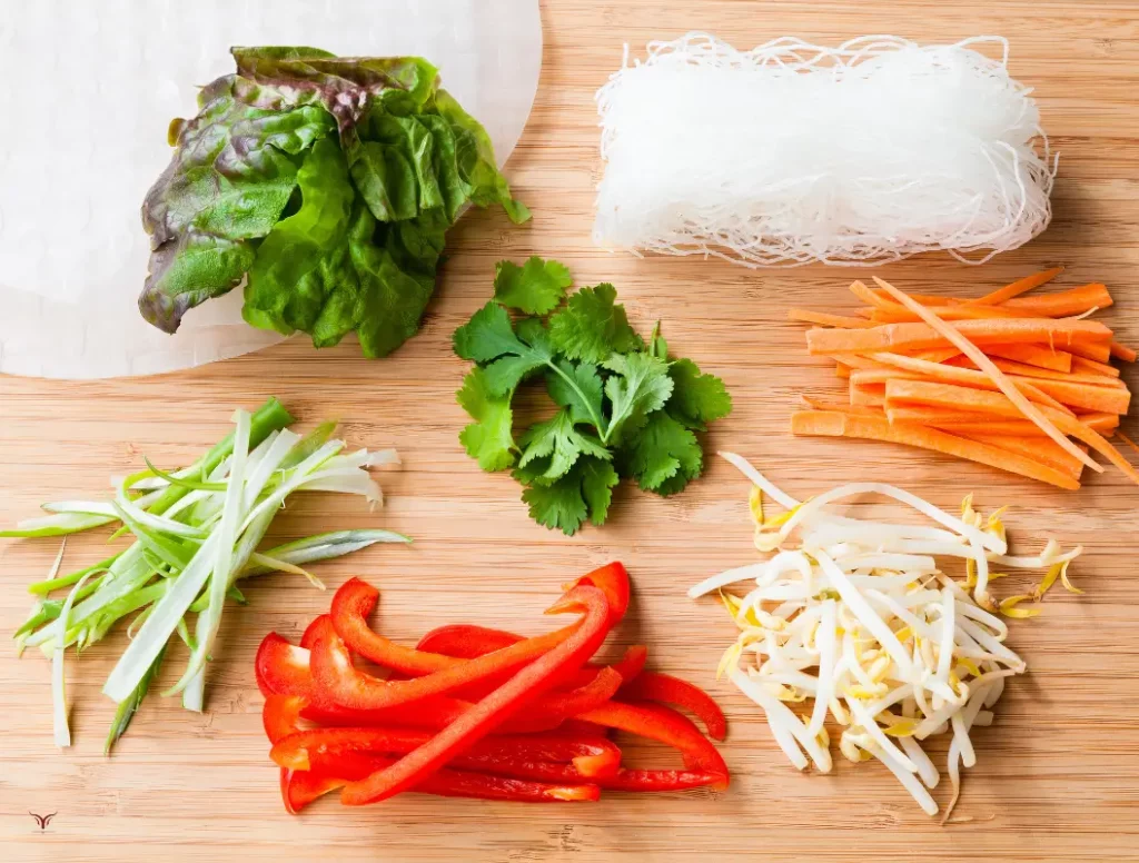Ingredients for Vegan Spring Rolls: shredded carrots, cucumber, rice vermicelli, mint leaves, and rice paper wrappers.