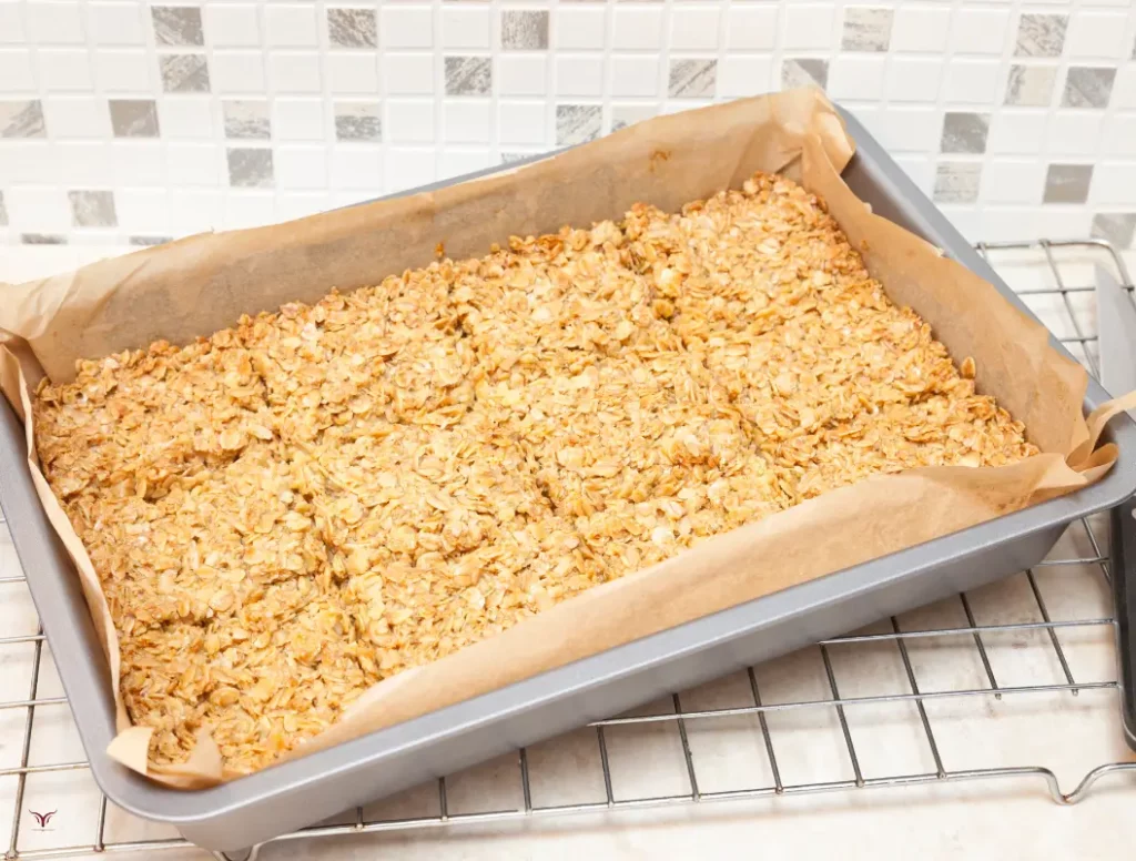 A tempting stack of fluffy, golden-brown flapjacks, fresh from the griddle, their surface textured with delicate ridges and crowned with a light dusting of powdered sugar. Glistening slices of ripe banana and a drizzle of fragrant maple syrup adorn the top, creating a mouthwatering contrast of flavors and textures. The flapjacks are arranged on a rustic wooden board, with a background of lush greenery and soft, diffused lighting that casts a warm, inviting glow over the scene. The overall atmosphere is one of wholesome, artisanal goodness, perfectly capturing the essence of a healthy, homemade flapjack. healthy flapjack recipe